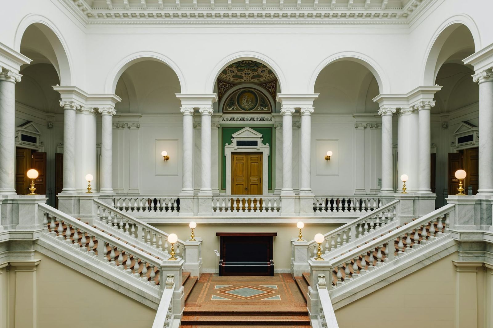 Grand hall classique aux colonnes de marbre blanc et à double escalier, baigné de lumière
